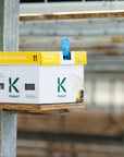 A packaged product labeled 'Natupol Excel' by Koppert placed on a wooden shelf in a greenhouse