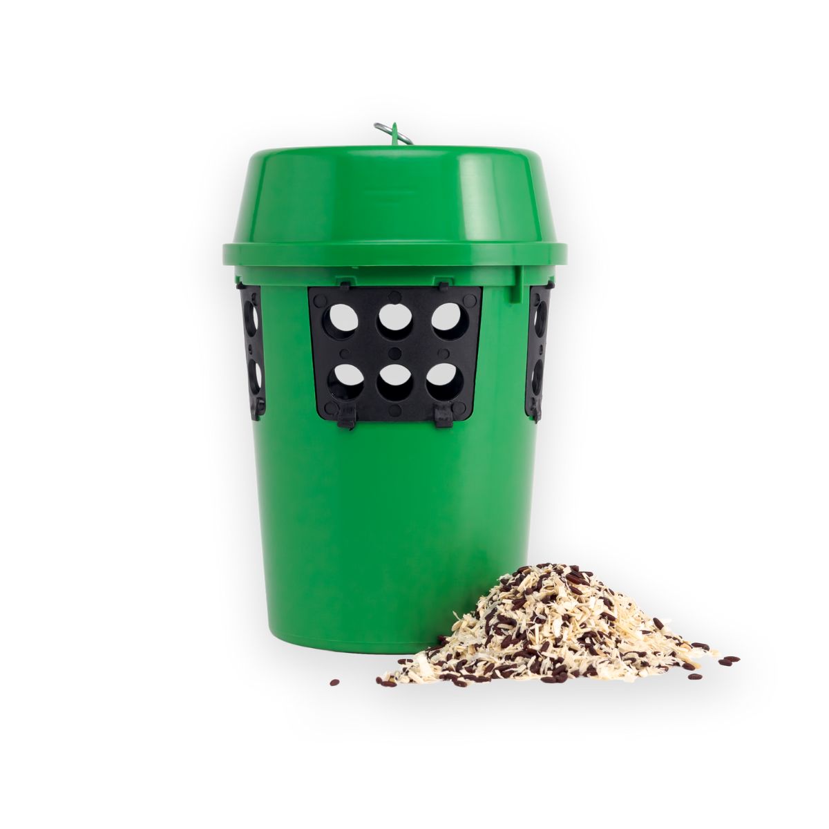 A green cylindrical release station with black attachments and holes on the side, accompanied by a pile of feed beside it.