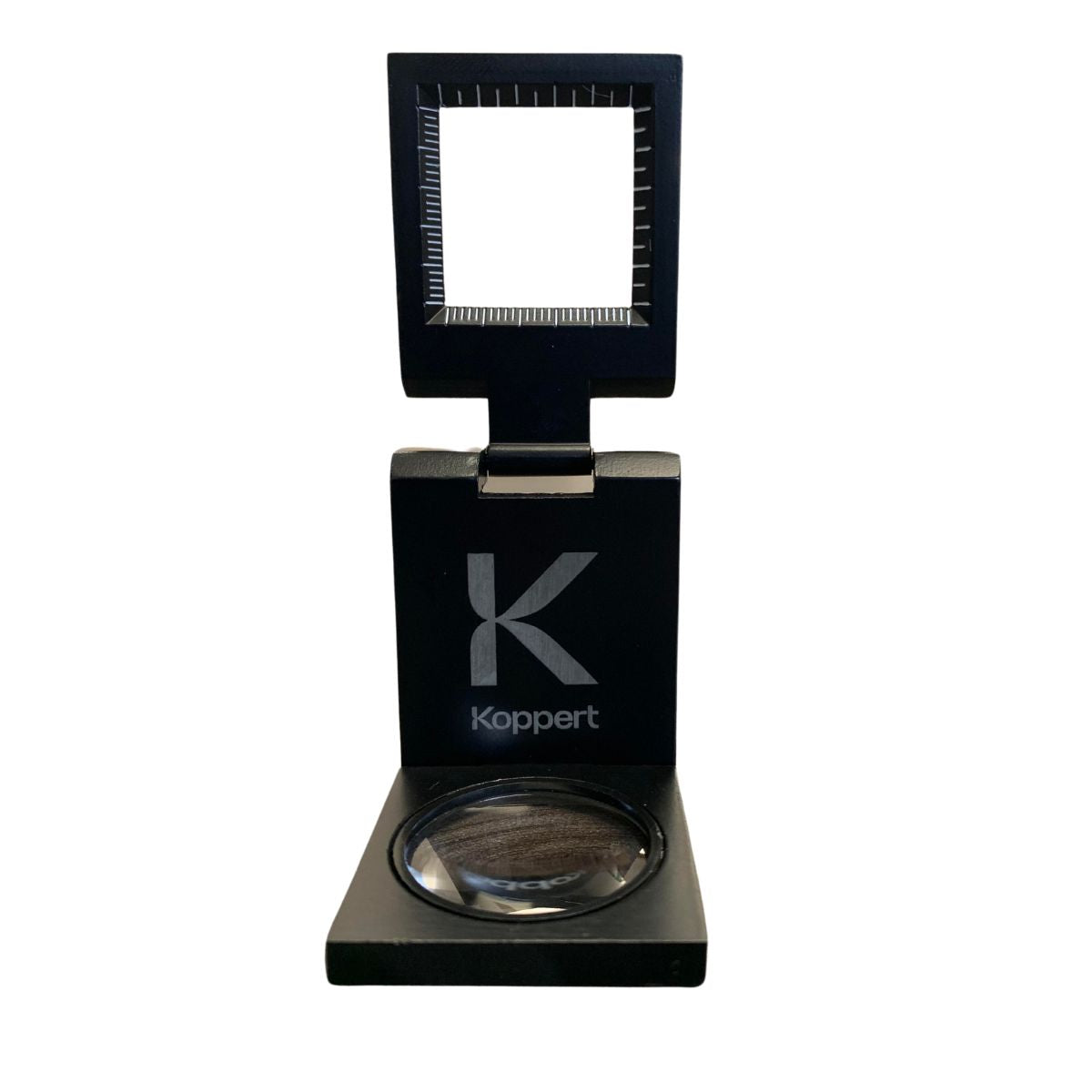 A black metal magnifying lens with a scale, displayed alongside its black protective case, featuring the brand name 'Koppert' on the lens.